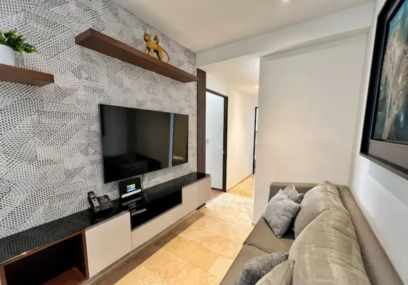 Een moderne woonkamer met een grote flatscreen-televisie, ingebouwde kasten, een bank en een kamer met een patroon op de muur.