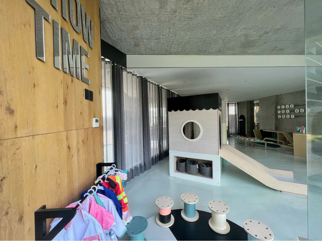 A modern interior with a wooden wall, a play area, and a seating area with a view.