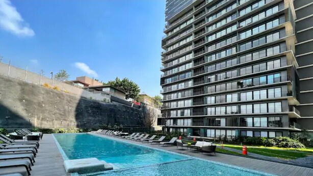 Ein modernes Gebäude mit Poolanlage, einschließlich Liegestühlen und einem klaren, blauen Pool.