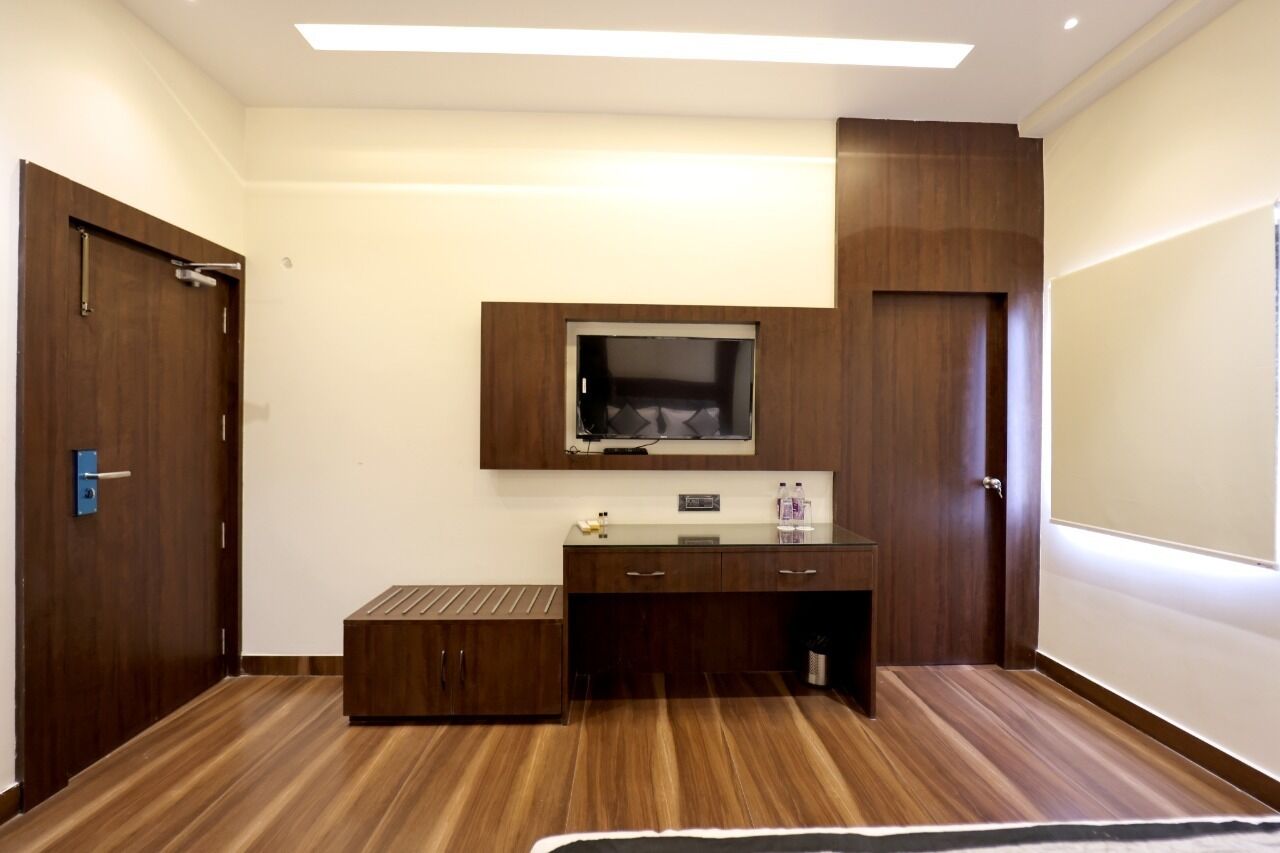 Une pièce avec un plancher en bois, un téléviseur encastré, un petit meuble et une porte.