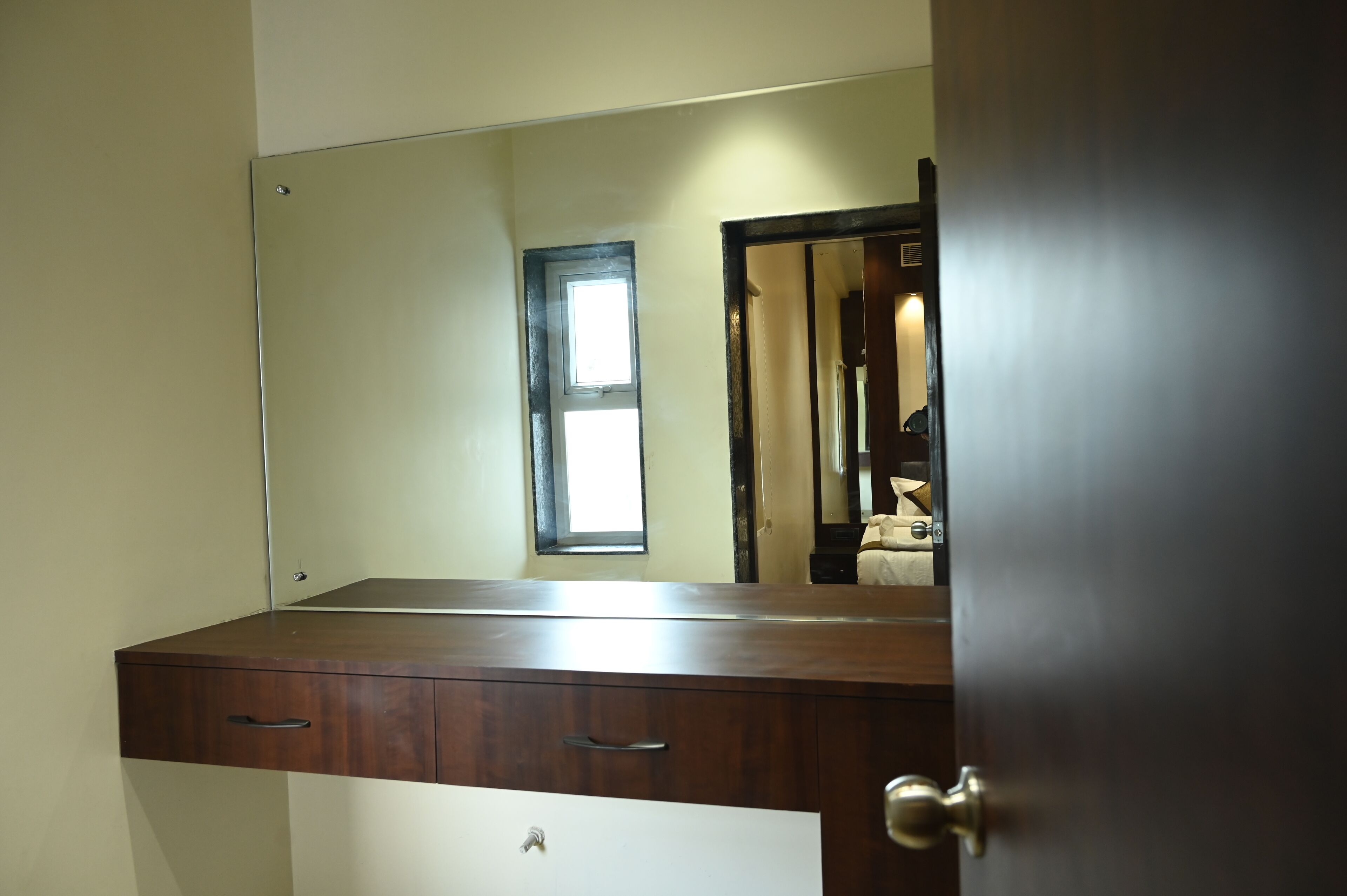 A room with a wooden dresser, a mirror, and a door.