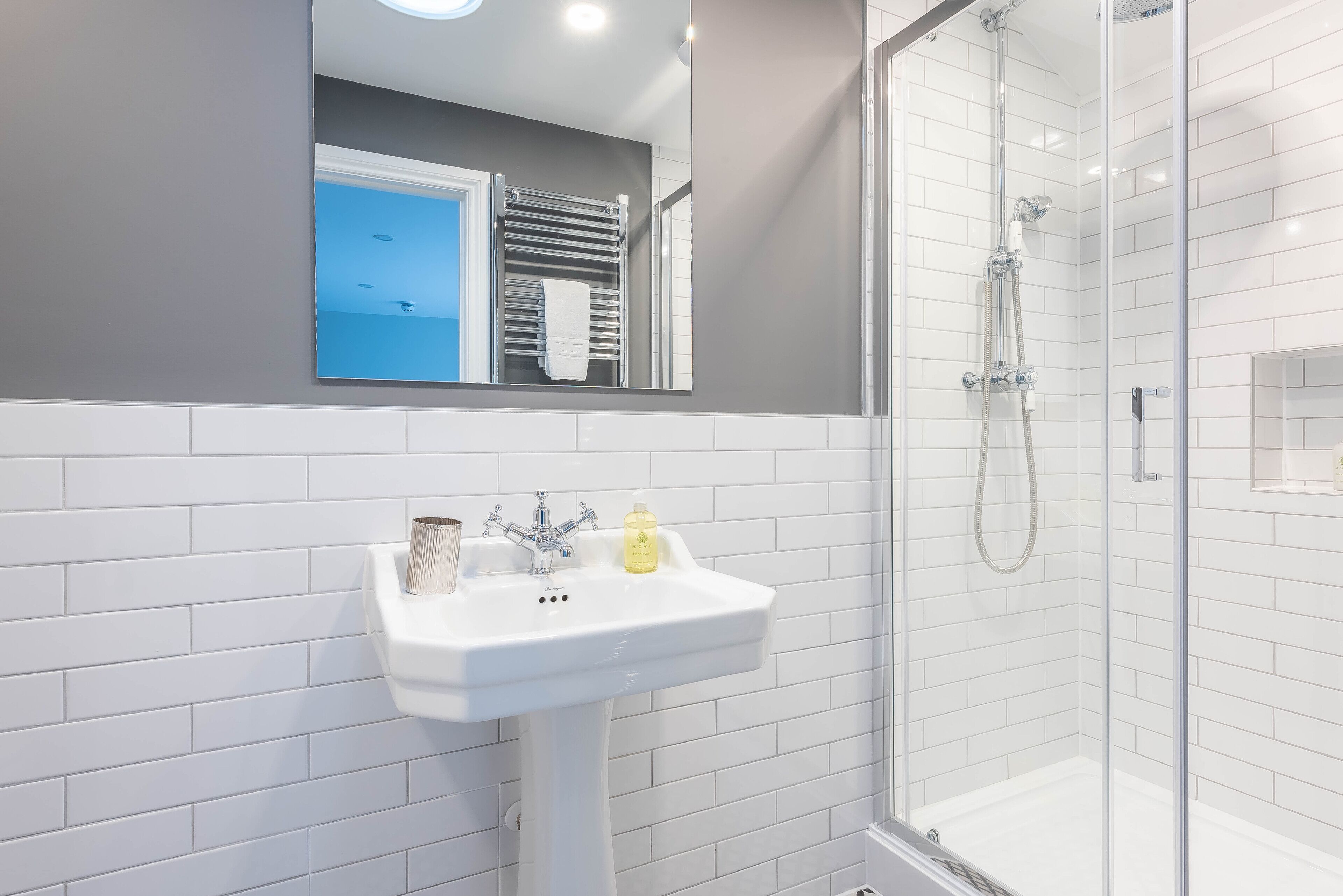 A bathroom with a white sink, a mirror, and a glass-enclosed shower.