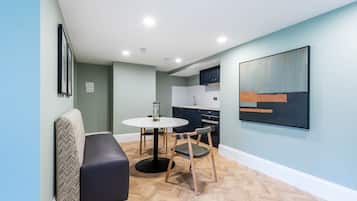A modern living room with a sofa, a dining table, and a kitchen in the background.