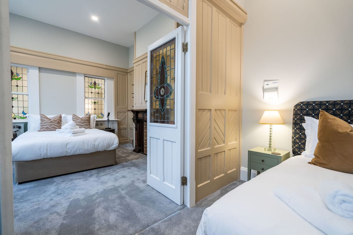 Een hotelkamer met twee bedden, een deur, een nachtkastje en een lamp.