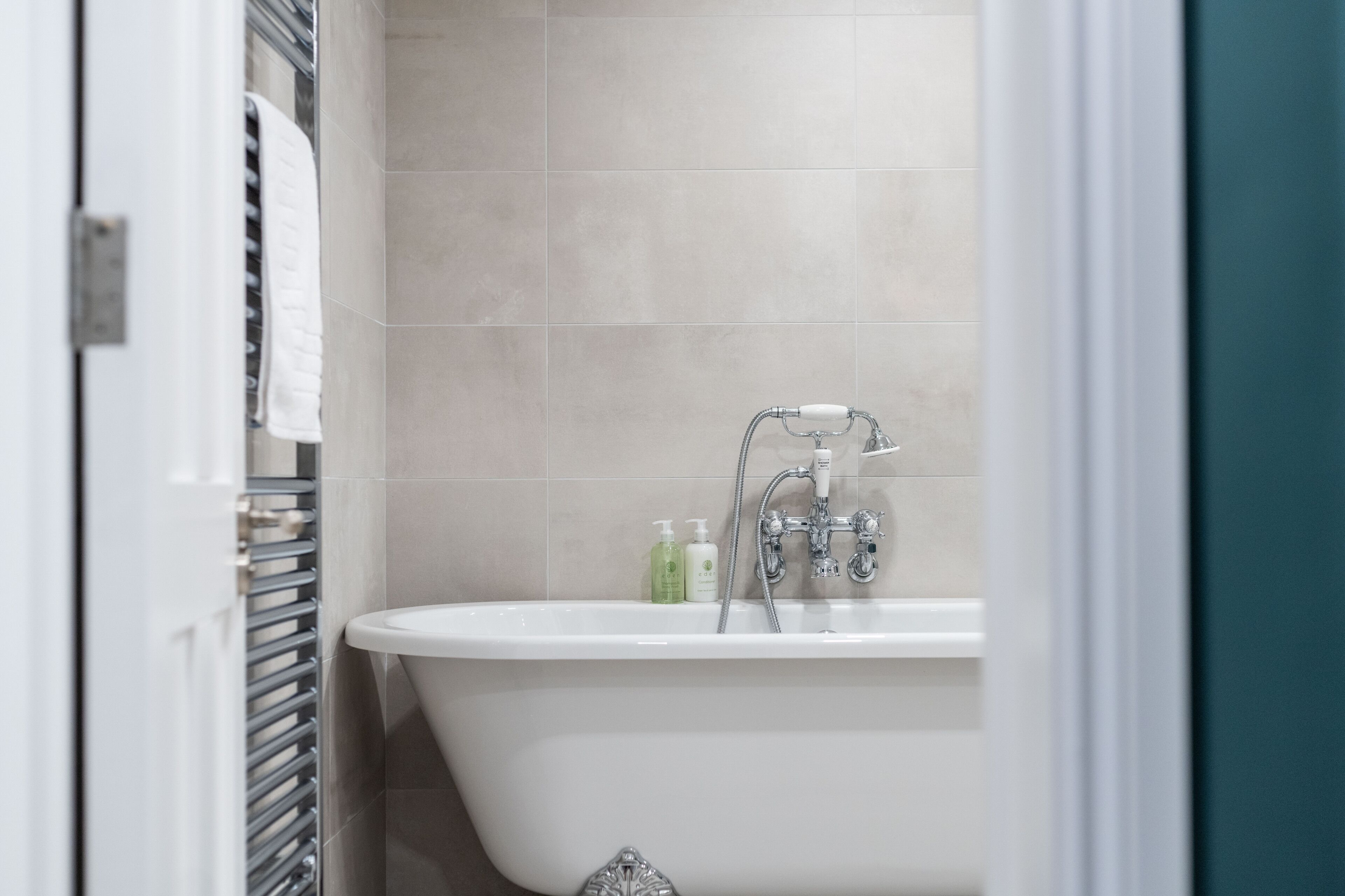 Un bagno con una vasca freestanding, un portasciugamani e due flaconi di sapone liquido a parete.