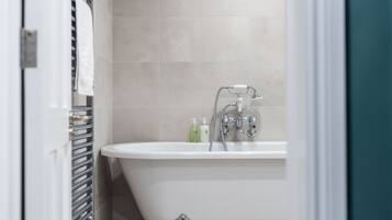 Un bagno con una vasca freestanding, un portasciugamani e due flaconi di sapone liquido a parete.
