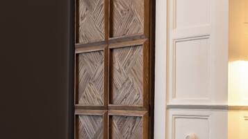 Een kamer met een grote houten garderobe, een wit kastje en een grijs vloerkleed.