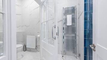 A modern bathroom with a glass shower enclosure, a white toilet, and a chrome towel rack.