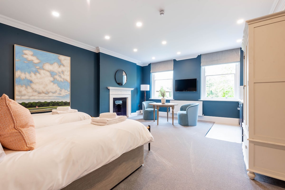 Een slaapkamer met een groot bed, een open haard, een televisie en een raam met uitzicht.