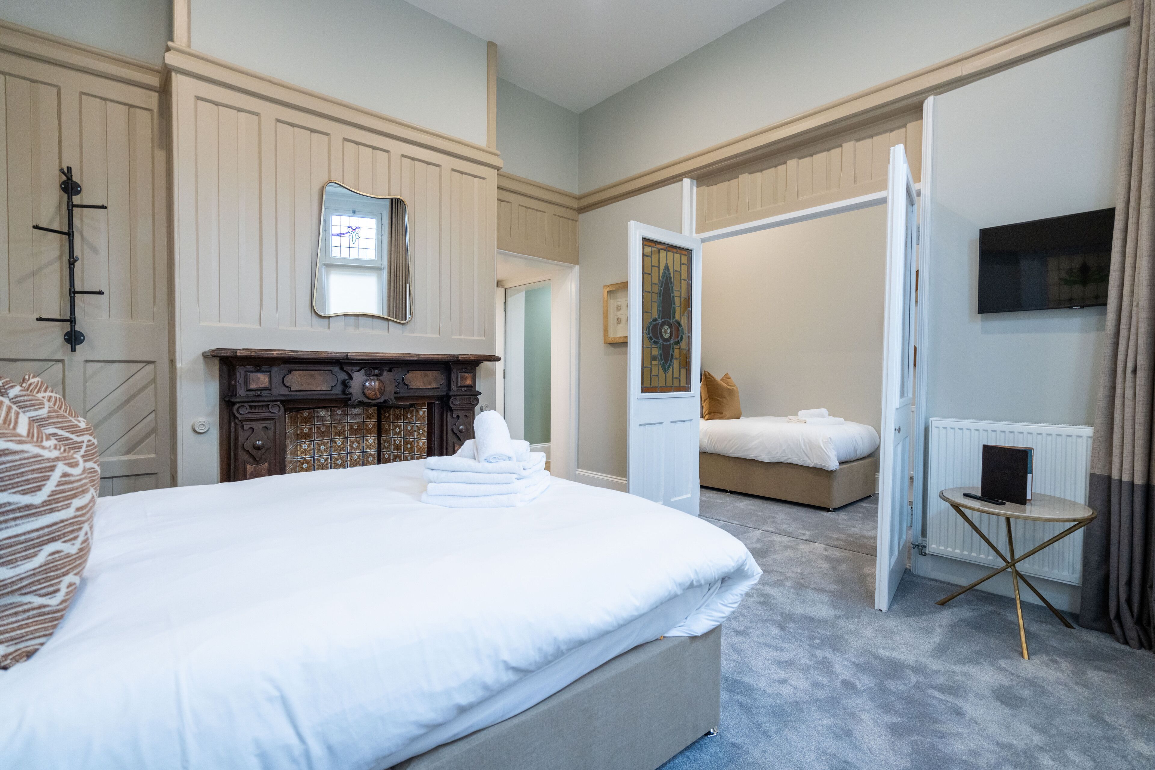 Una habitación de hotel con una cama grande, un aparador de madera, un espejo y un televisor en la pared.