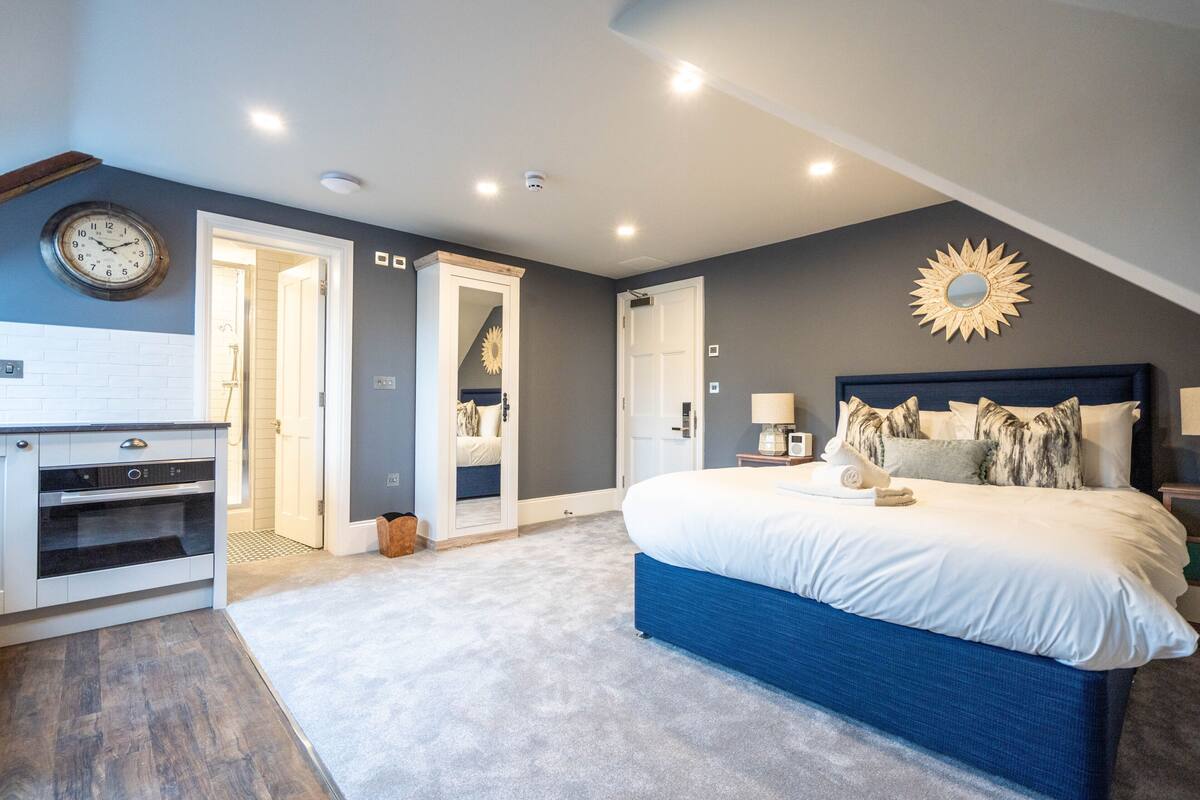 Een slaapkamer met een groot bed, een inbouw bureau en een wandklok.