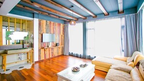 Una sala de estar con piso de madera, un sofá, una mesa de centro, un televisor y una pared de acento de madera.