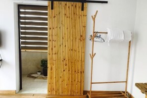 Una habitación con puerta corredera, perchero y una pequeña mesa.