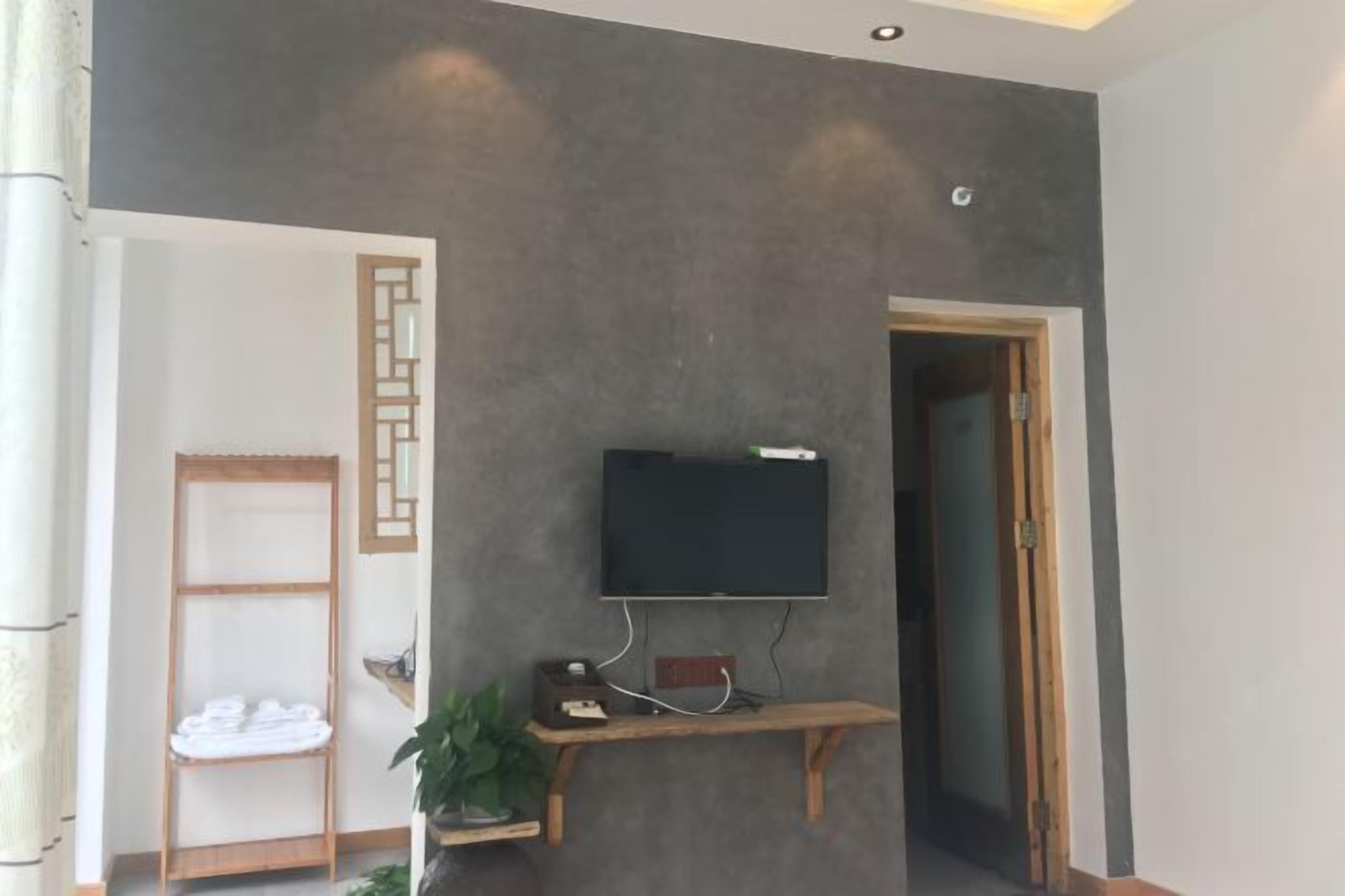 Une pièce dotée d’un téléviseur à écran plat fixé sur une console en bois, d’un porte-serviettes et d’une porte donnant sur une autre pièce.