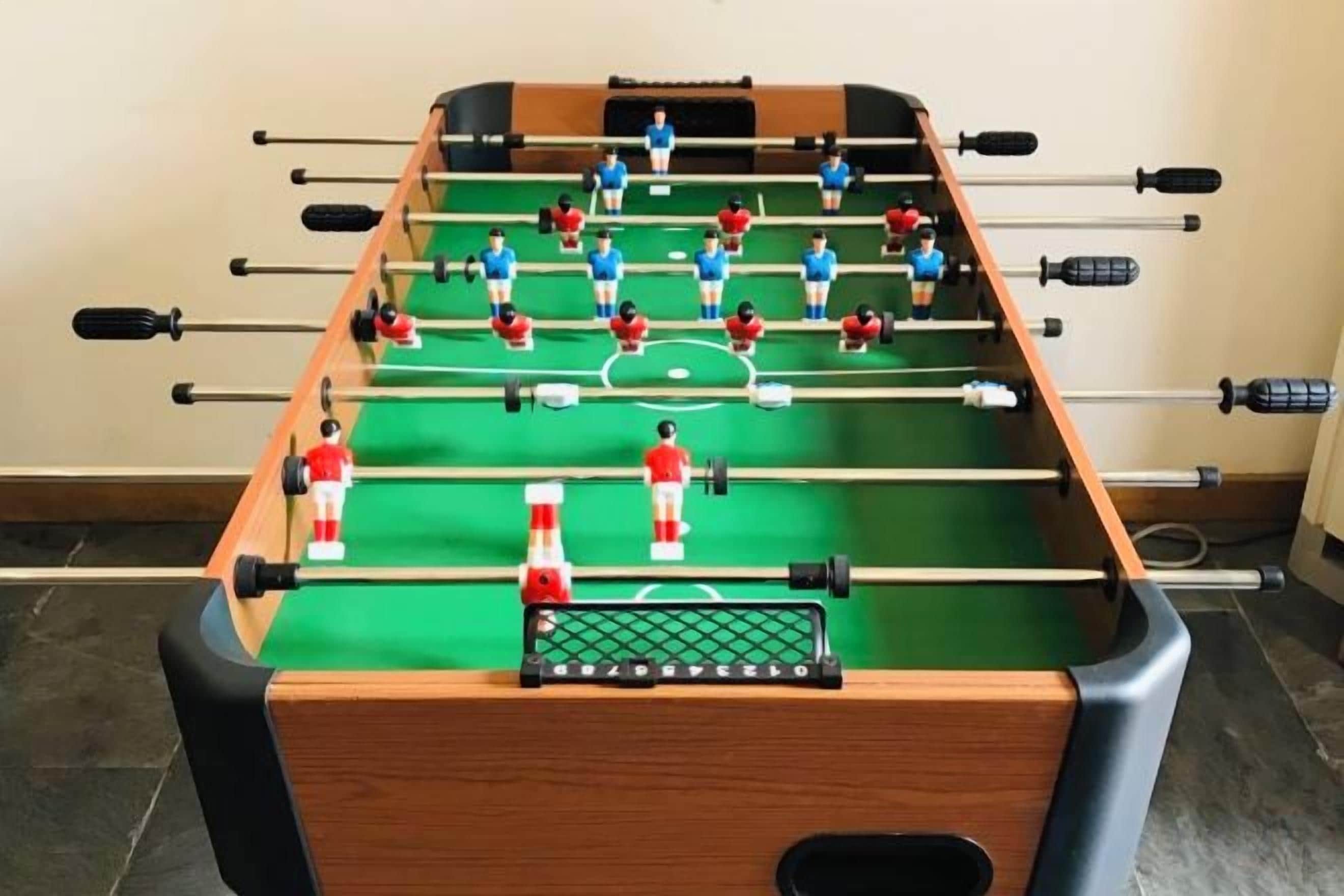 Une table de baby-foot avec un tapis de jeu vert et plusieurs tiges.