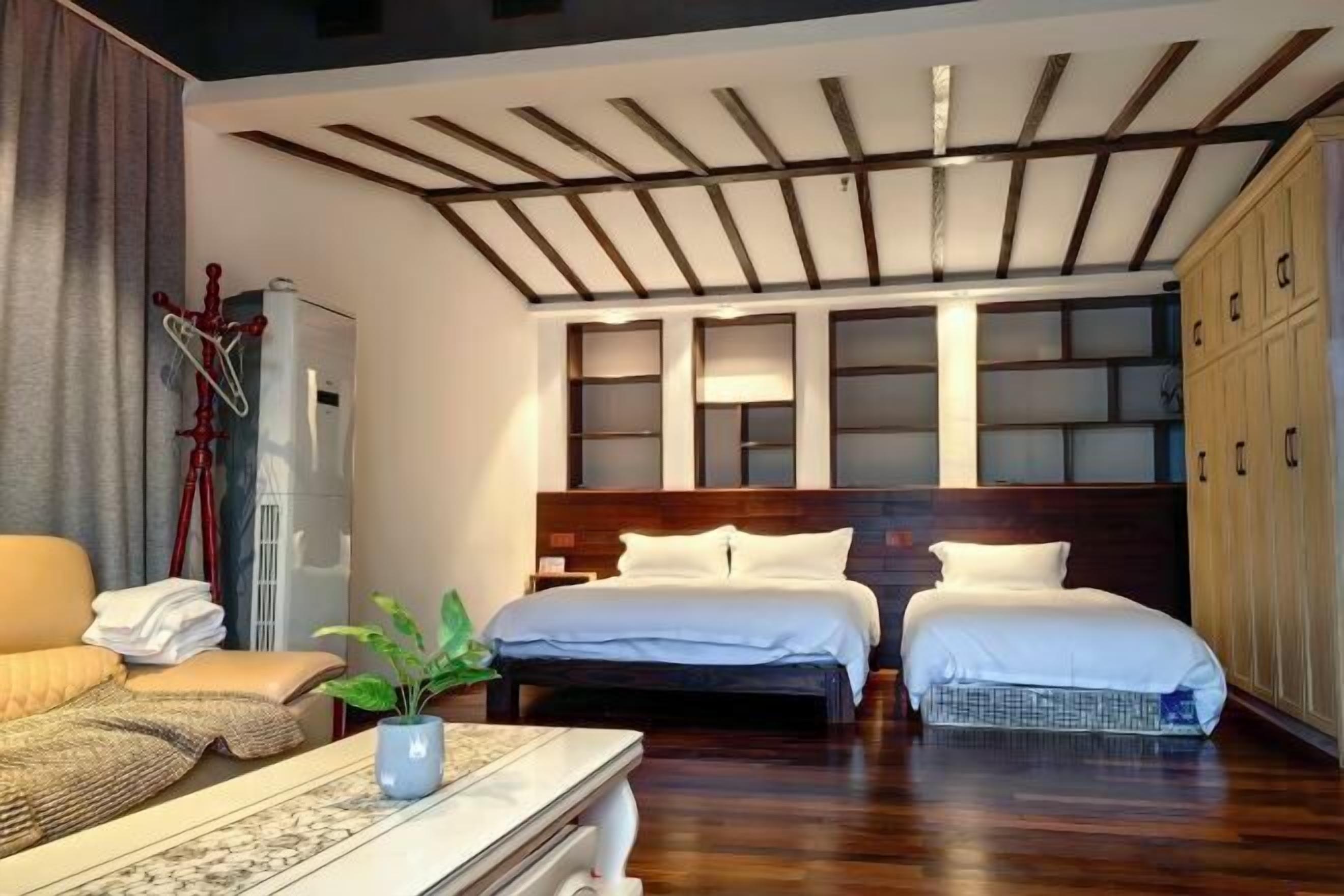 Una habitación de hotel con techo de madera, dos camas, un sofá, un escritorio y un armario.