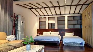 Una habitación de hotel con techo de madera, dos camas, un sofá, un escritorio y un armario.