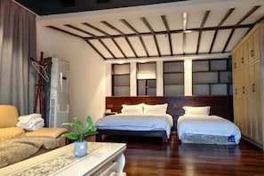 Quarto de hotel com teto de madeira, duas camas, um sofá, uma escrivaninha e um guarda-roupa.