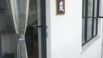 Une porte avec une enseigne au-dessus, une fenêtre et un rideau qui recouvre partiellement la porte.