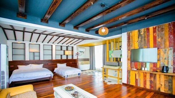 Habitación de hotel con dos camas, un sofá, una mesa de centro, un televisor y una pared colorida.