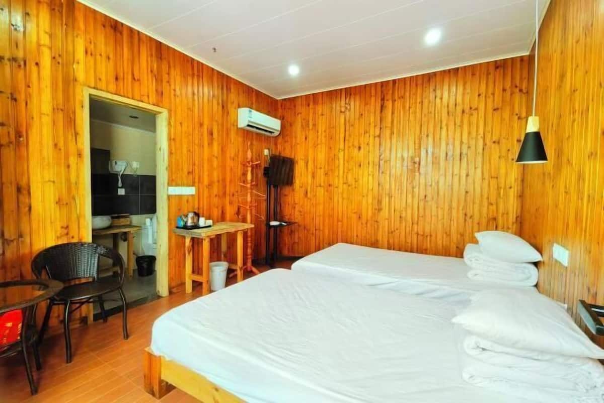 Una habitación con paneles de madera, una cama, una silla, una mesa y un equipo de aire acondicionado.