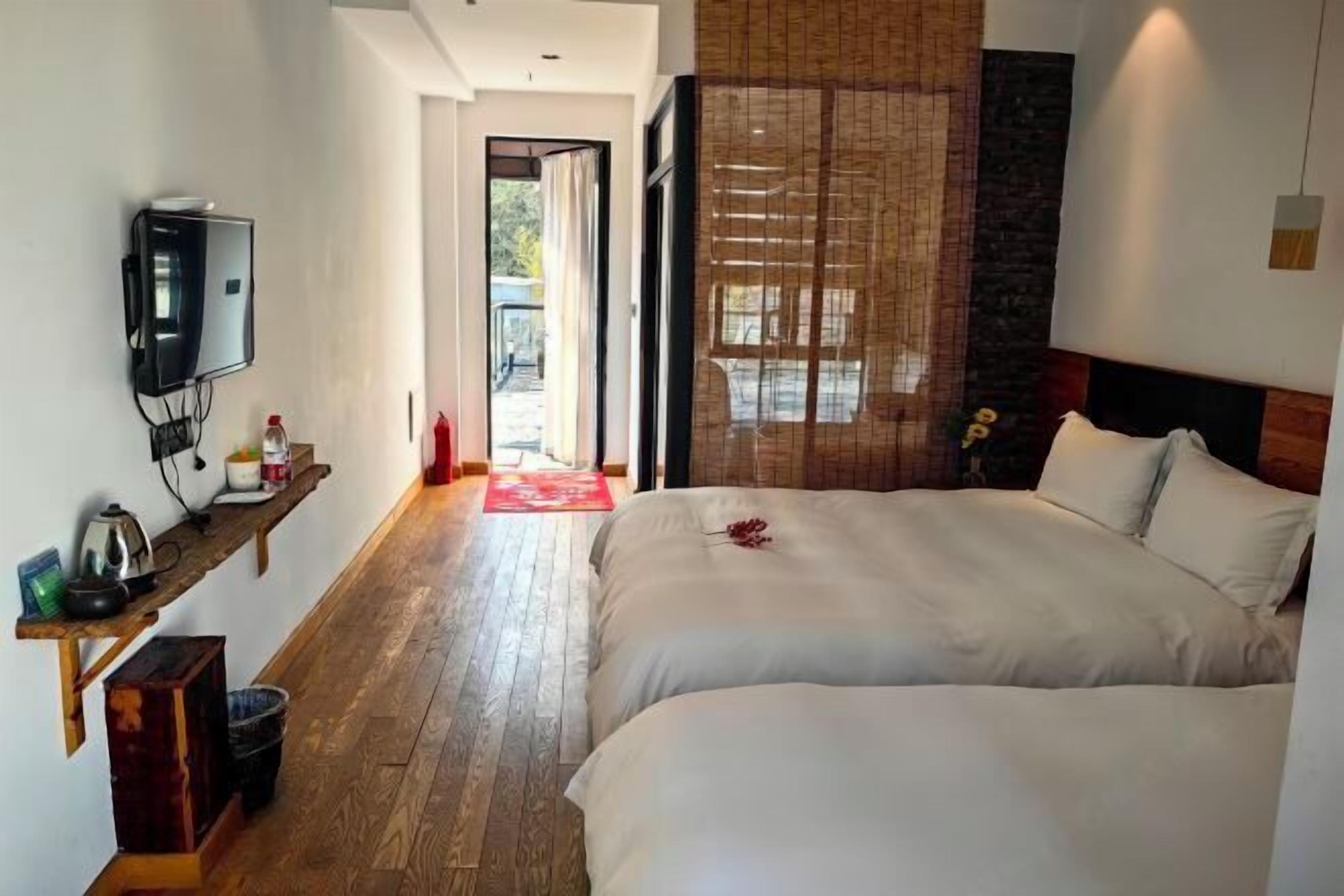 Une chambre d’hôtel avec un lit, une télévision, une étagère avec quelques objets et une vue sur l’extérieur.