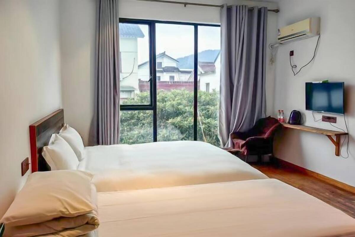 Una habitación de hotel con una cama grande, televisión y ventana con cortinas.