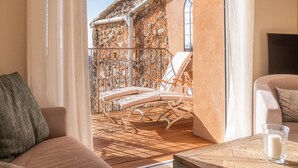Ein Balkon mit Steinmauer, Holzboden und einem weißen Stuhl.