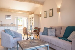 A modern living room with a sofa, armchairs, a coffee table, and a dining area with chairs and a table.