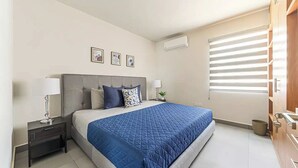 Un dormitorio moderno con una cama grande, una mesita de noche y una ventana con persianas.