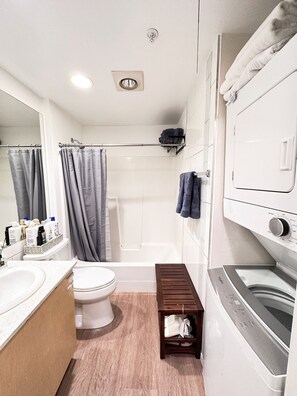 A modern bathroom with a toilet, shower, and built-in washing machine.
