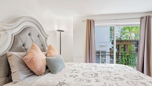 A bedroom with a tufted headboard, a patterned bedspread, and a view of a balcony with a railing. - 321 Getaway in Seattle Center-Belltown (Seattle)