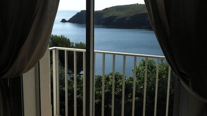 Een balkon met uitzicht op zee en heuvels.