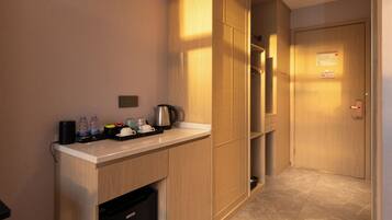 A hotel room with a wooden cabinet, a small kitchen area, and a door with a sign.