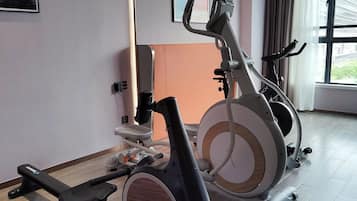 Ett gym med två motionscyklar, en bänk och en TV som är monterad på väggen.