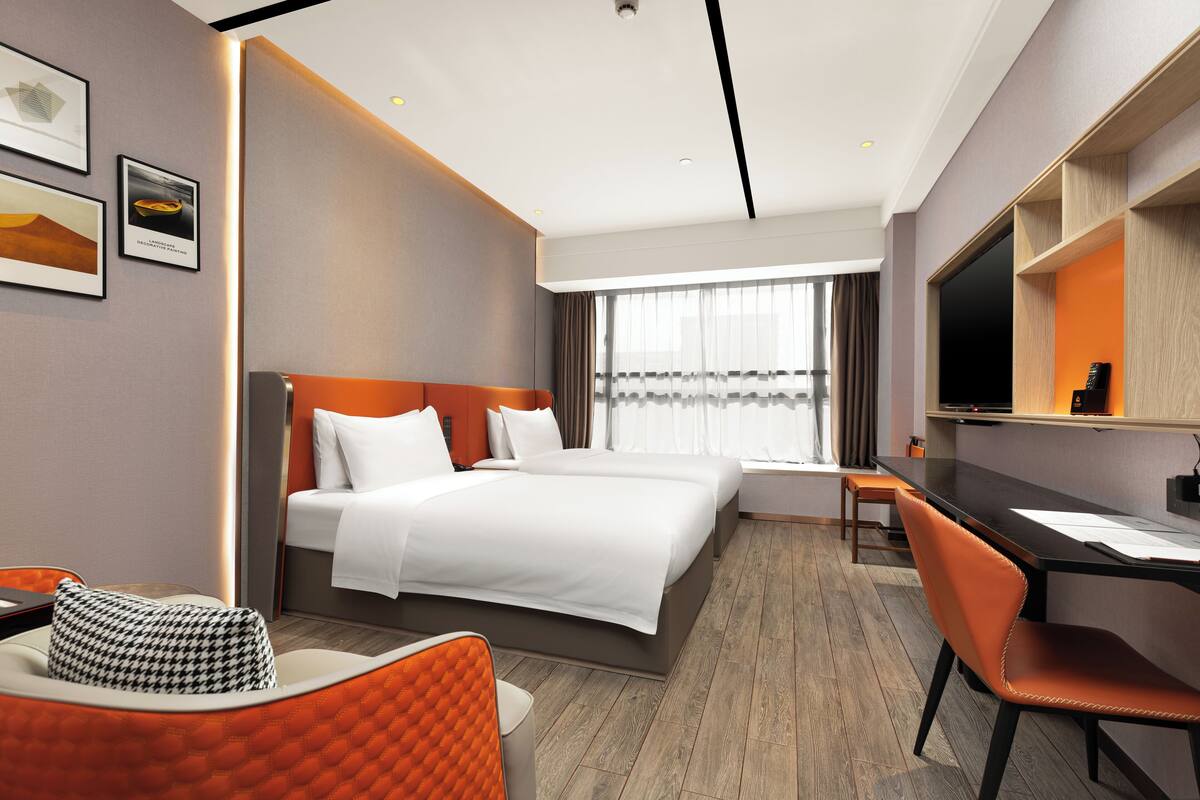 A modern hotel room with a large bed, a desk, and a television.