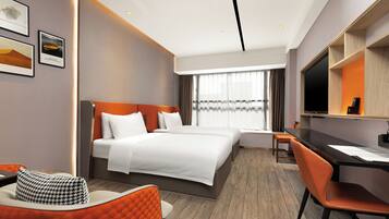 A modern hotel room with a large bed, a desk, and a television.