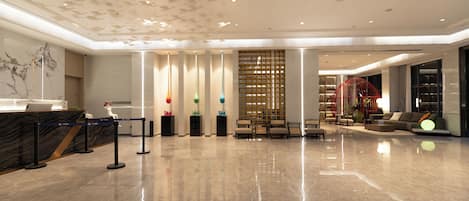 A spacious lobby with a marble floor, a reception desk, and a seating area with a modern design.