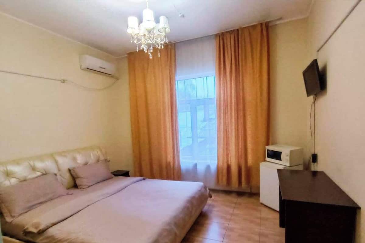 A bedroom with a bed, a desk, a television, and a microwave.