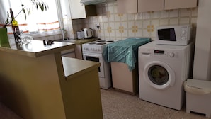Una cocina compacta con lavadora, microondas y estufa.
