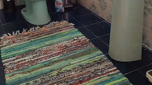 Un baño con inodoro, lavamanos y un tapete a rayas en el suelo.