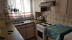 Cocina compacta con pileta, estufa y ventana con cortinas.