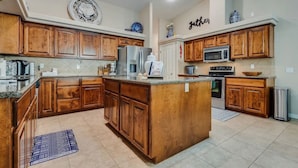 A spacious kitchen with wooden cabinets, a central island, and modern appliances. - Havasu Cabana - Pool, Spa, Games, Lake View, Garage (Lake Havasu City)
