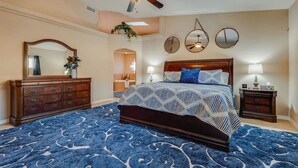 A bedroom with a large bed, a dresser, a ceiling fan, and a mirror. - Havasu Cabana - Pool, Spa, Games, Lake View, Garage (Lake Havasu City)