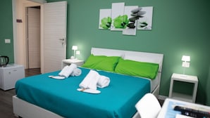A hotel room with a bed, green walls, and a painting of flowers. - Napoli Botanik Bed and Breakfast (Naples)