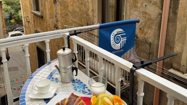 A balcony with a table set for breakfast, including croissants, orange slices, and a coffee pot. - Napoli Botanik Bed and Breakfast (Naples)