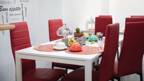 A dining area with a white table, red chairs, and a variety of tableware and decorative items. - Napoli Botanik Bed and Breakfast (Naples)