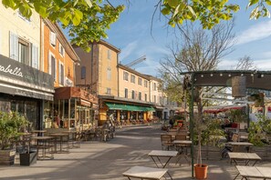 Une rue avec des terrasses, un glacier et un café.