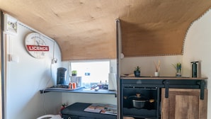 Een kleine keuken met een klok, een koffiezetapparaat, een kleine koelkast en een houten kastje.