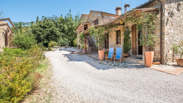 Un bâtiment en pierre avec un chemin de gravier, des portes en bois et des plantes en pot.